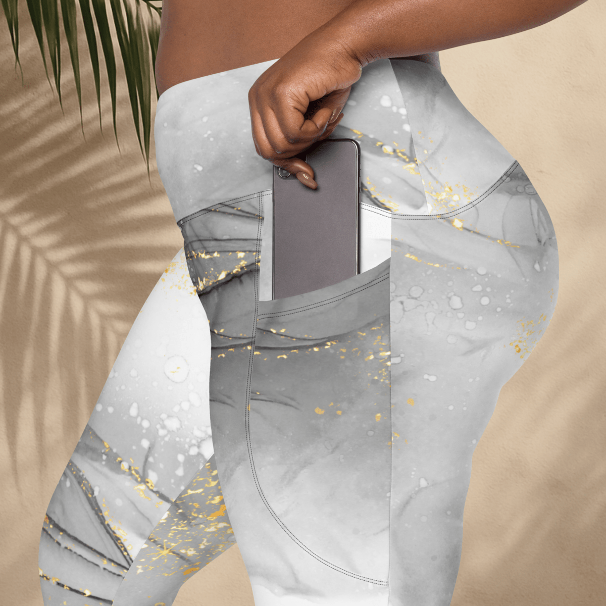Gray leggings with gold glitter pattern worn by a person, against a beige background.