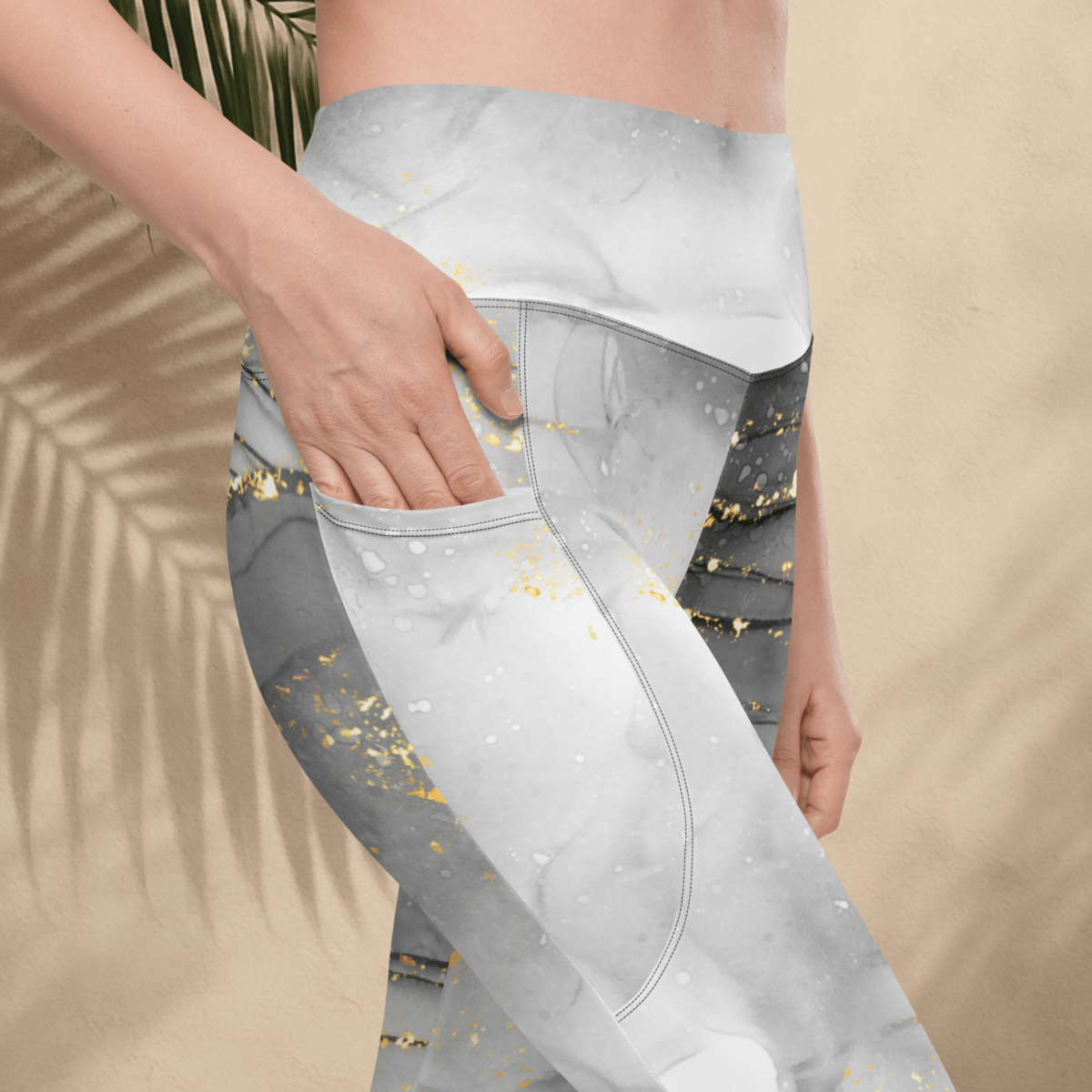 Gray leggings with gold speckles worn by a person against a beige background