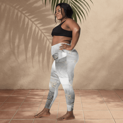 Woman wearing gray and white patterned leggings and black sports bra standing against a beige wall.