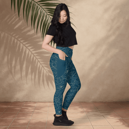 Woman wearing teal floral patterned leggings and black top against a beige wall.