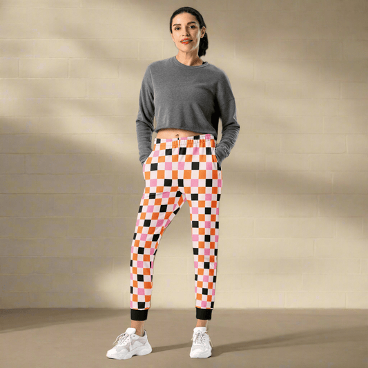 Woman wearing a gray long-sleeve top and colorful checkered pants against a beige background