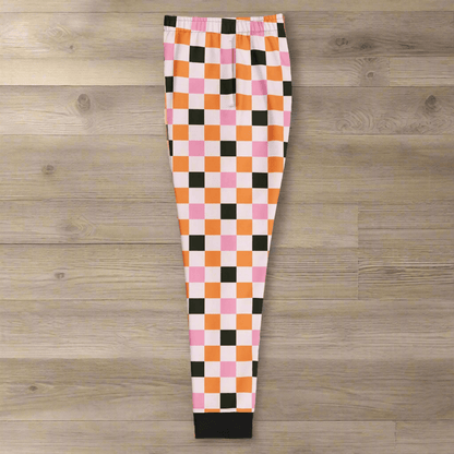 Checkered pants with pink, orange, and black squares on a wood background