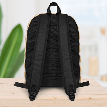 Backside of a backpack on a wooden surface with a blurred plant and light-colored wall in the background