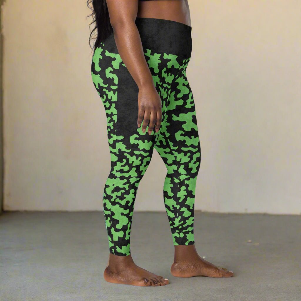 Green and black camouflage leggings worn by a person on a neutral background