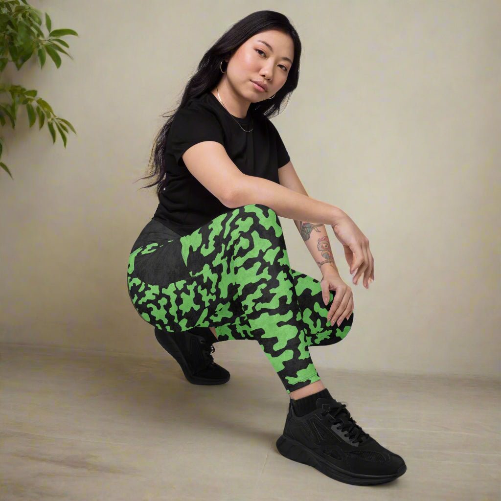 Person wearing green camouflage leggings and black shoes on a neutral background