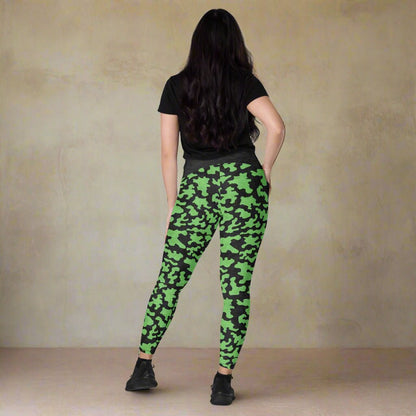 Person wearing green camouflage leggings on a neutral background
