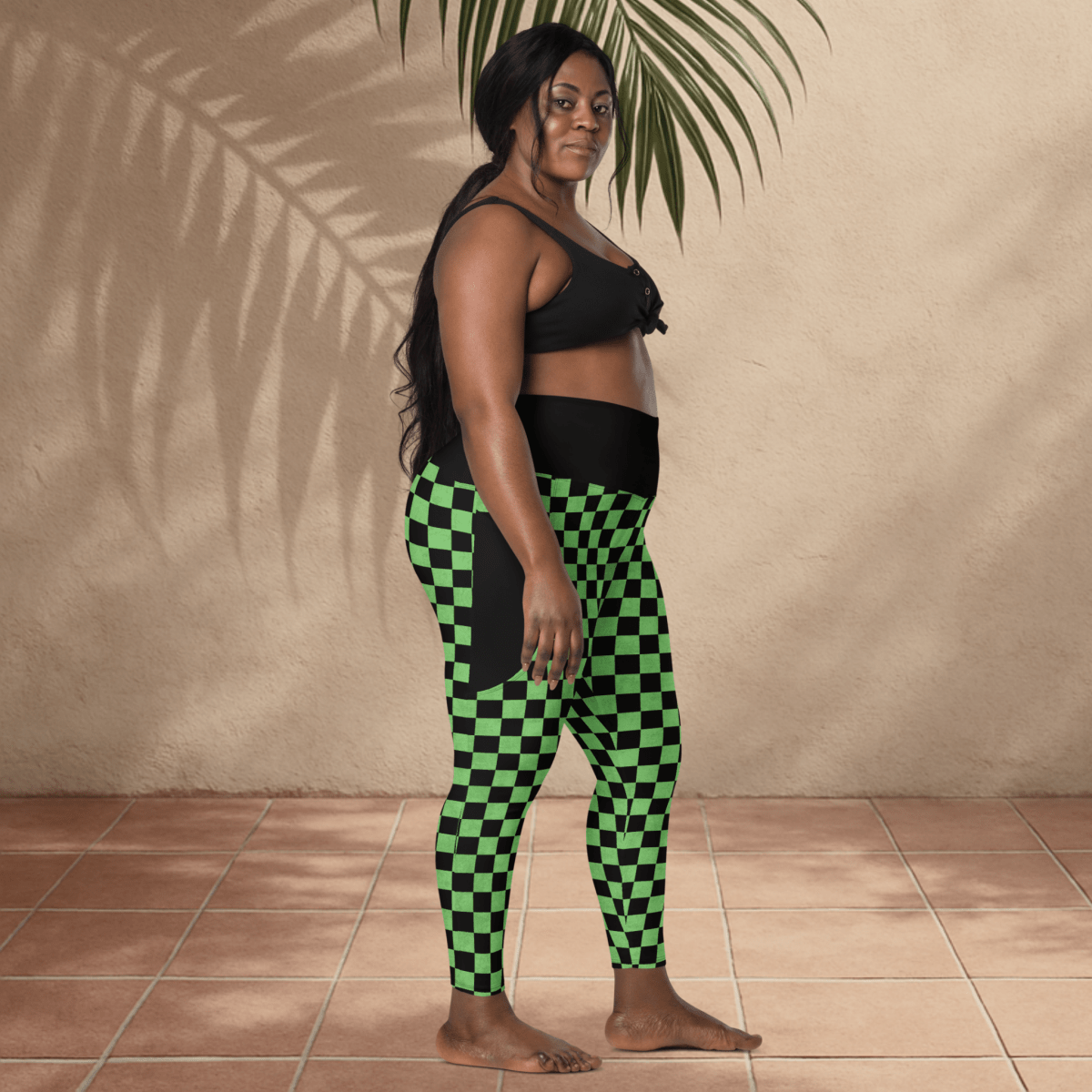 Woman wearing black and green checkered leggings against a beige wall.