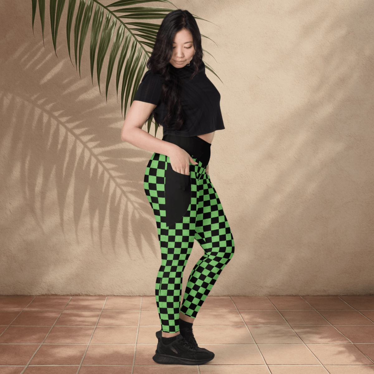 Woman wearing green and black checkered pants against a beige wall.