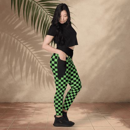 Woman wearing green and black checkered pants against a beige wall.