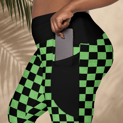 Person wearing black and green checkered leggings with a pocket holding a phone.