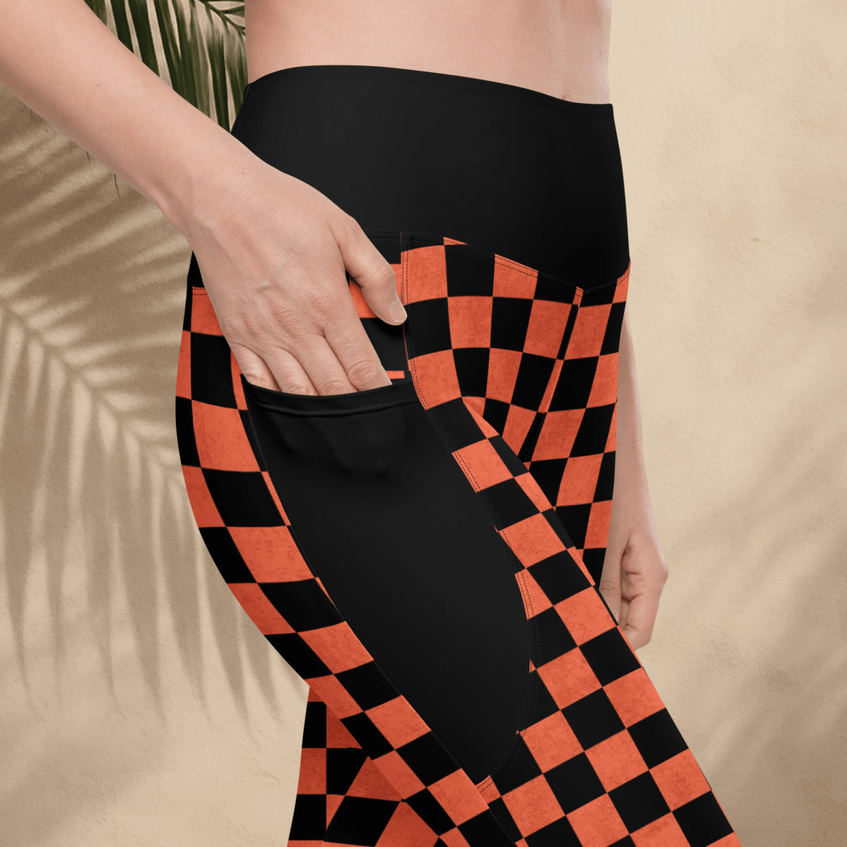 Person wearing black and orange checkered pants on a beige background