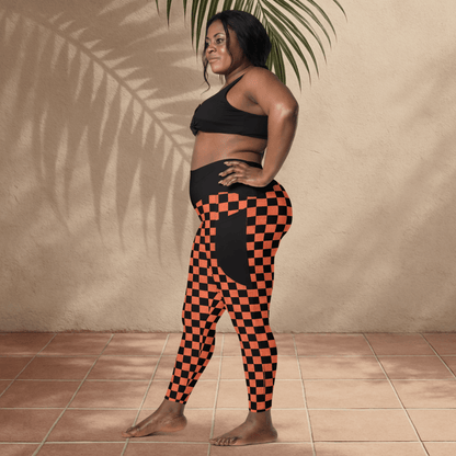 Woman wearing black and orange checkered leggings and black sports bra against a beige wall.