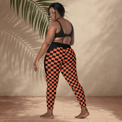 Person wearing black and orange checkered leggings against a beige wall.