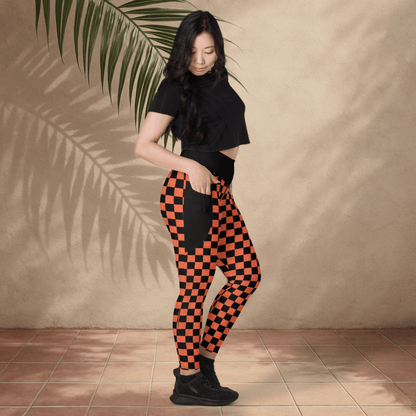 Woman wearing black and orange checkered pants against a beige wall.