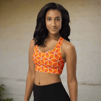 Woman wearing an orange geometric patterned sports bra on a neutral background