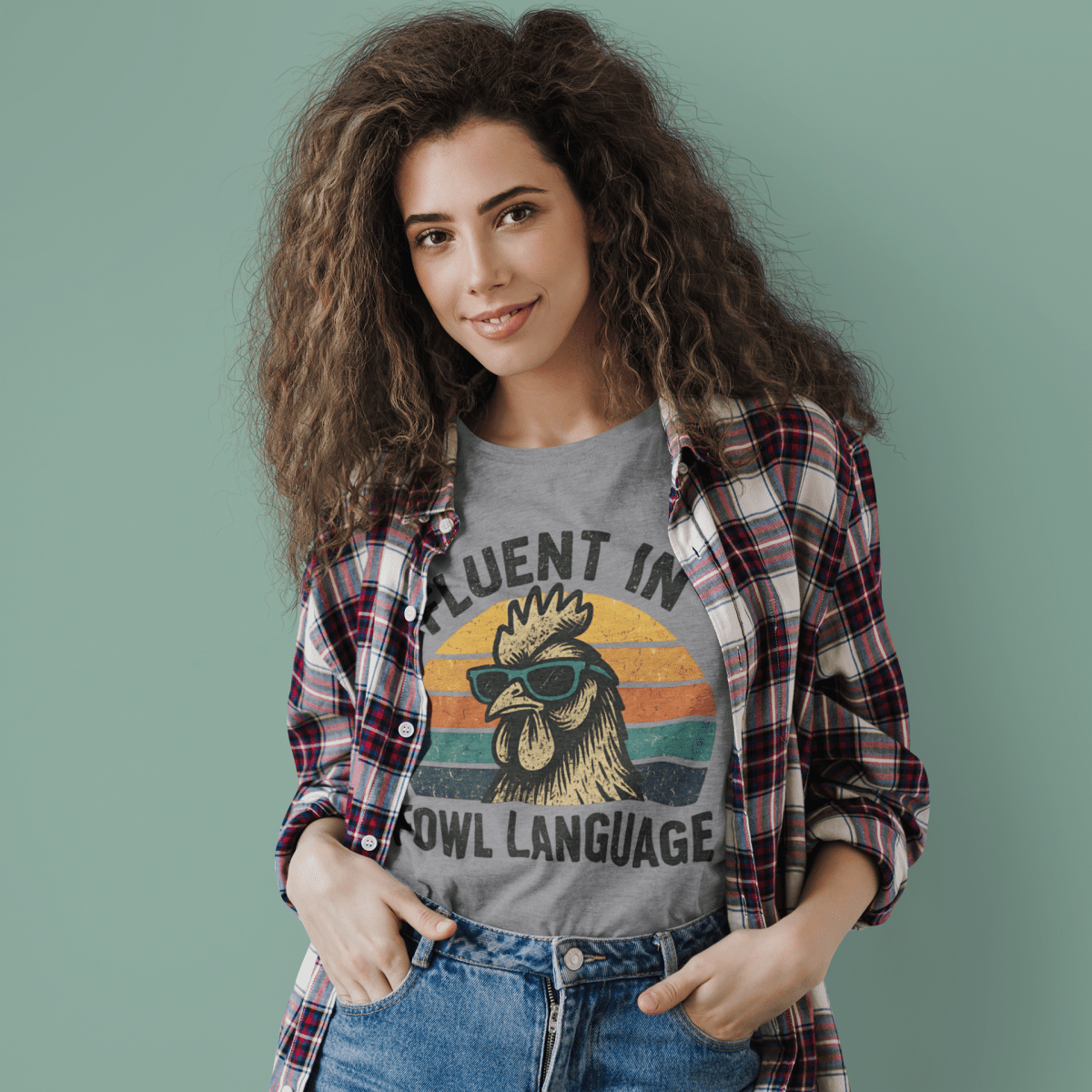 Woman wearing a gray t-shirt with a rooster graphic and text, standing against a plain background