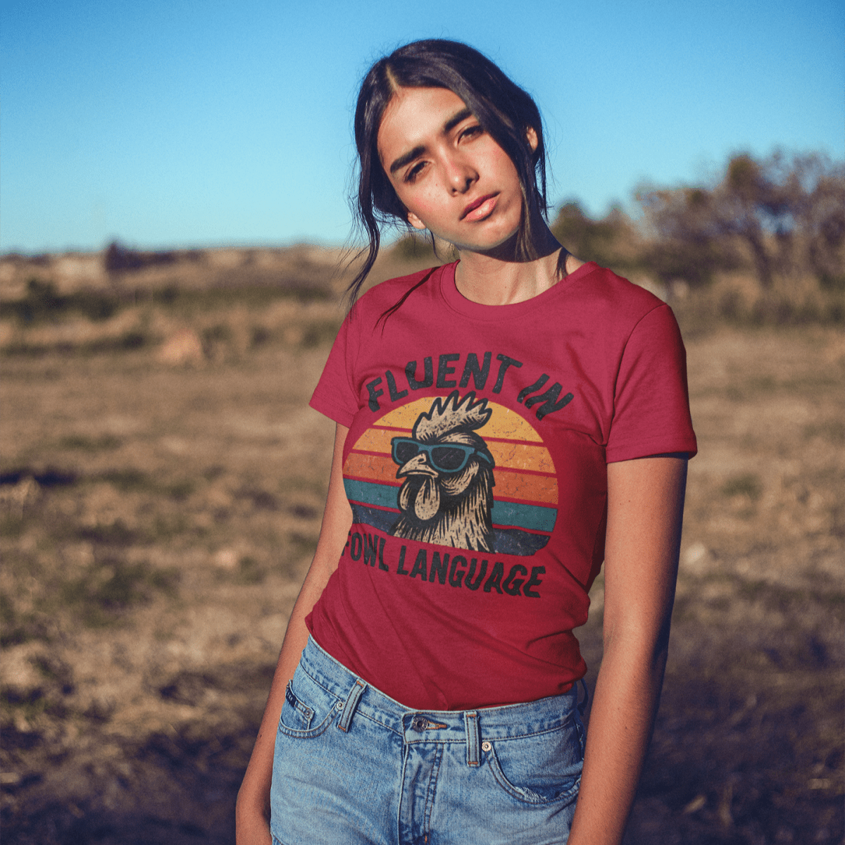 Person wearing a red t-shirt with a graphic design and text, standing in an outdoor setting.