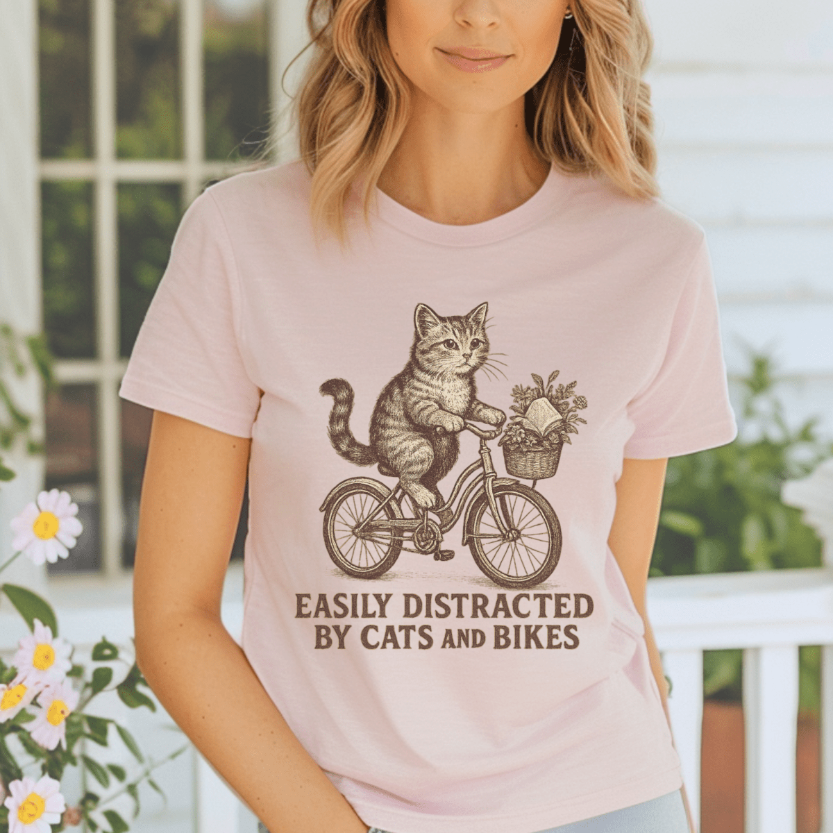 Person wearing a pink t-shirt with a cat riding a bike graphic and text.
