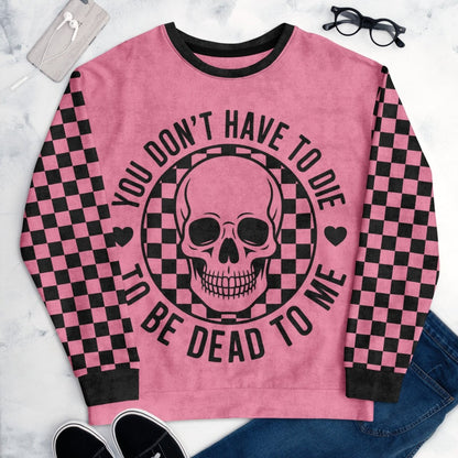 Pink sweatshirt with skull design and text on a marble surface
