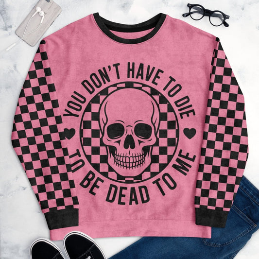 Pink sweatshirt with skull design and text on a marble surface