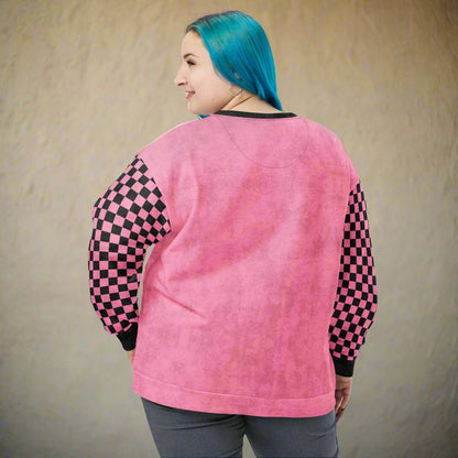 Person wearing a pink sweatshirt with checkered sleeves against a beige background