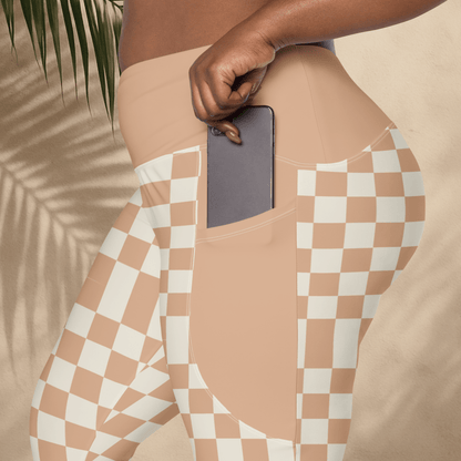 Person wearing peach leggings with a checkered pattern and pocket, holding a phone.
