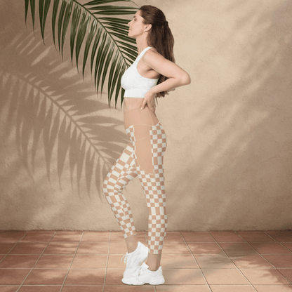 Woman wearing a white sports bra and checkered leggings against a beige wall with a palm leaf.