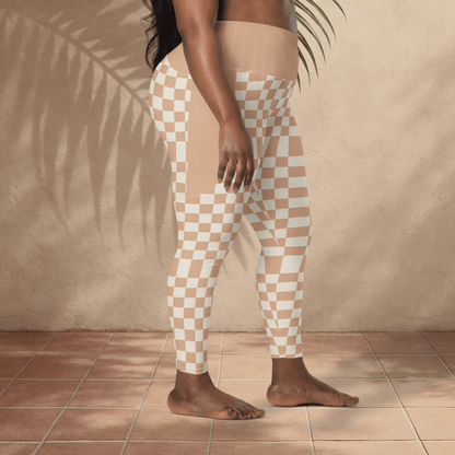 Person wearing checkered pants standing against a beige wall with a plant leaf in the background.