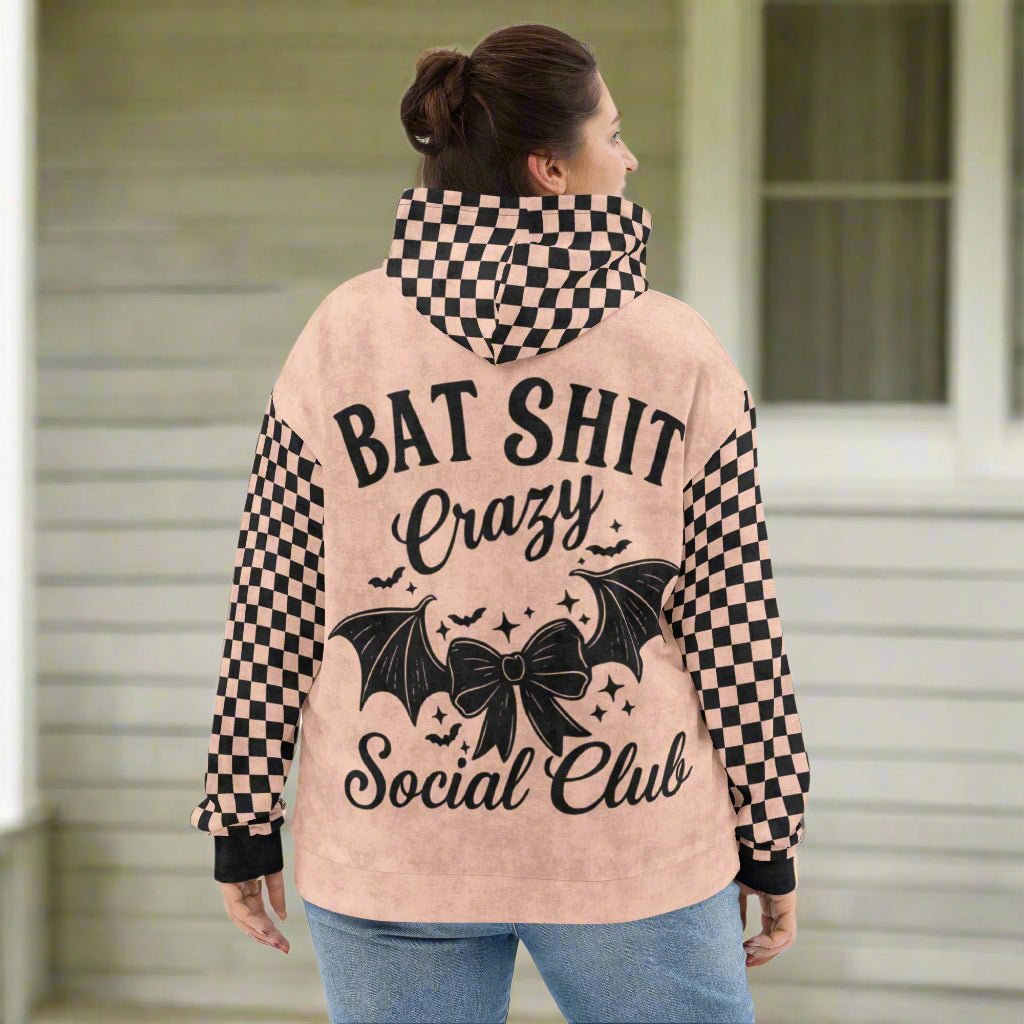 Person wearing a hoodie with 'Bat Shit Crazy Social Club' text and checkered sleeves 