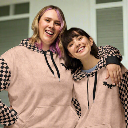 Two people wearing matching checkered hoodies with bat designs 