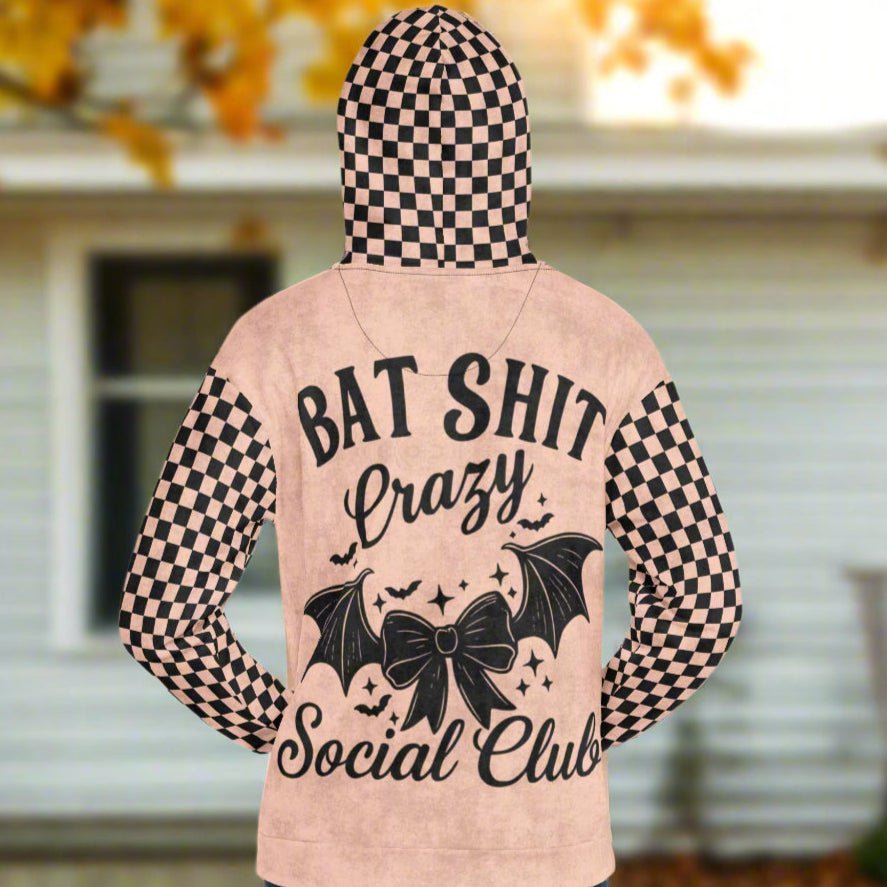 Peach hoodie with black text and checkered pattern on a blurred background