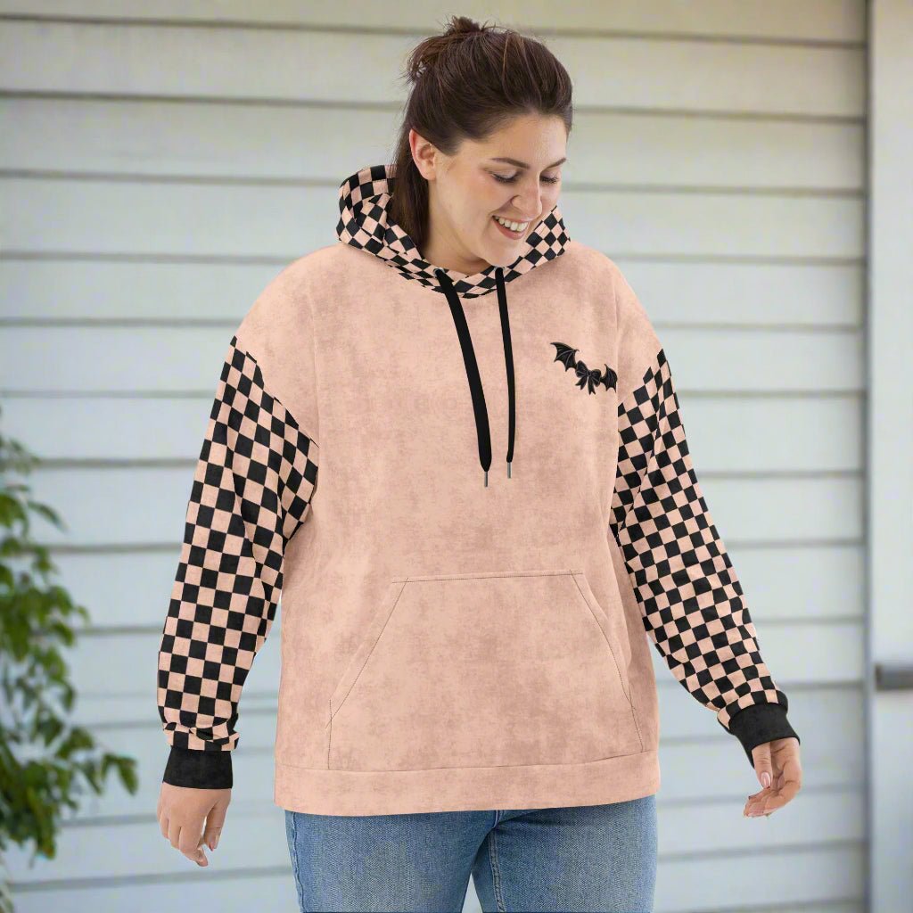 Woman wearing a peach hoodie with checkered sleeves and bat designs 