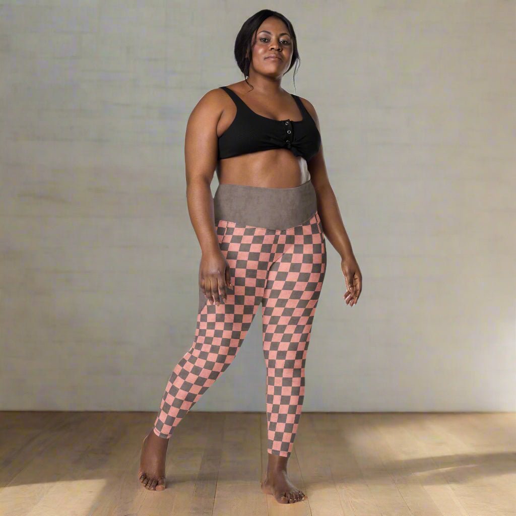 Woman wearing a black sports bra and pink checkered leggings on a white background