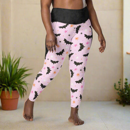 Pink leggings with black bat pattern worn by a person on a beige background