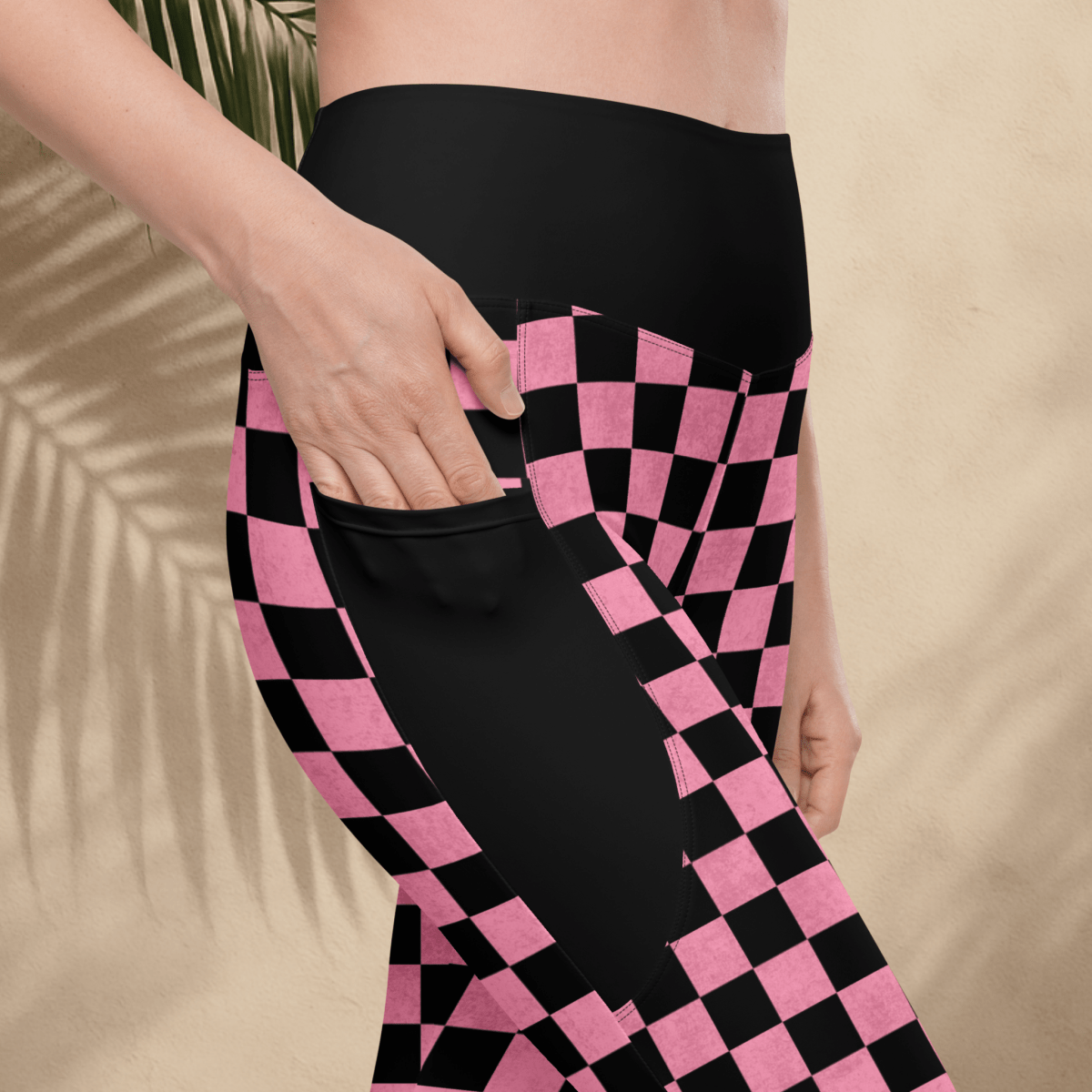 Person wearing black and pink checkered pants with a beige background