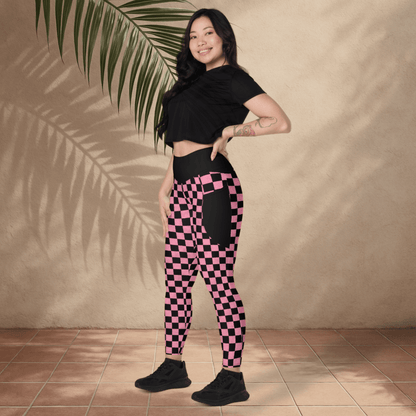 Woman wearing black and pink checkered leggings with a black crop top against a beige wall.
