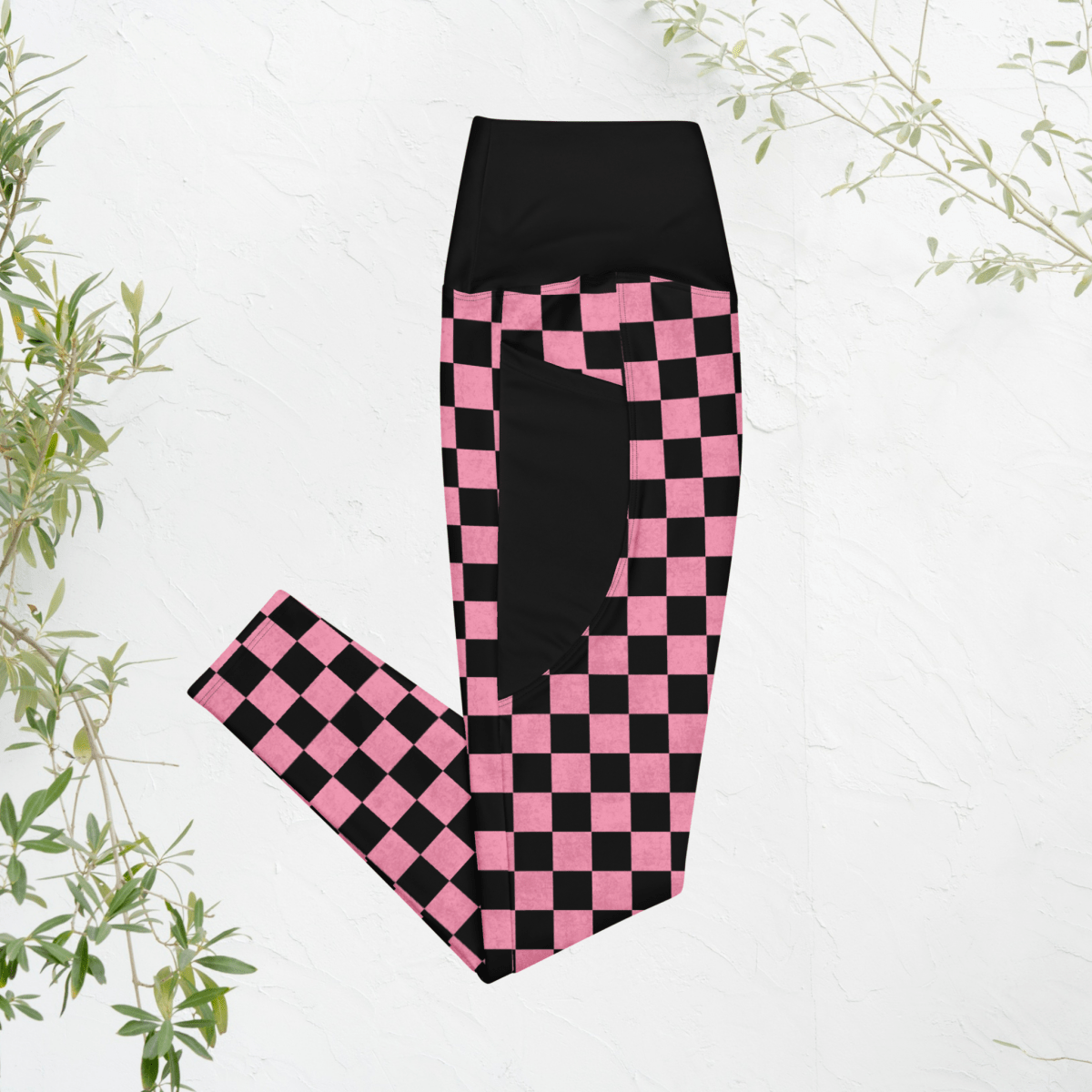 Black and pink checkered leggings on a white background with green leaves.