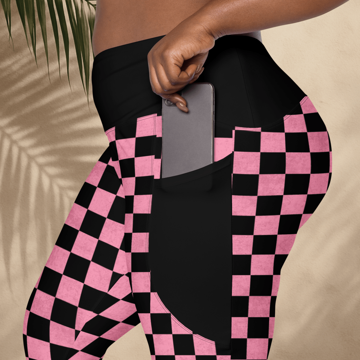 Person wearing black and pink checkered pants with a pocket holding a phone.