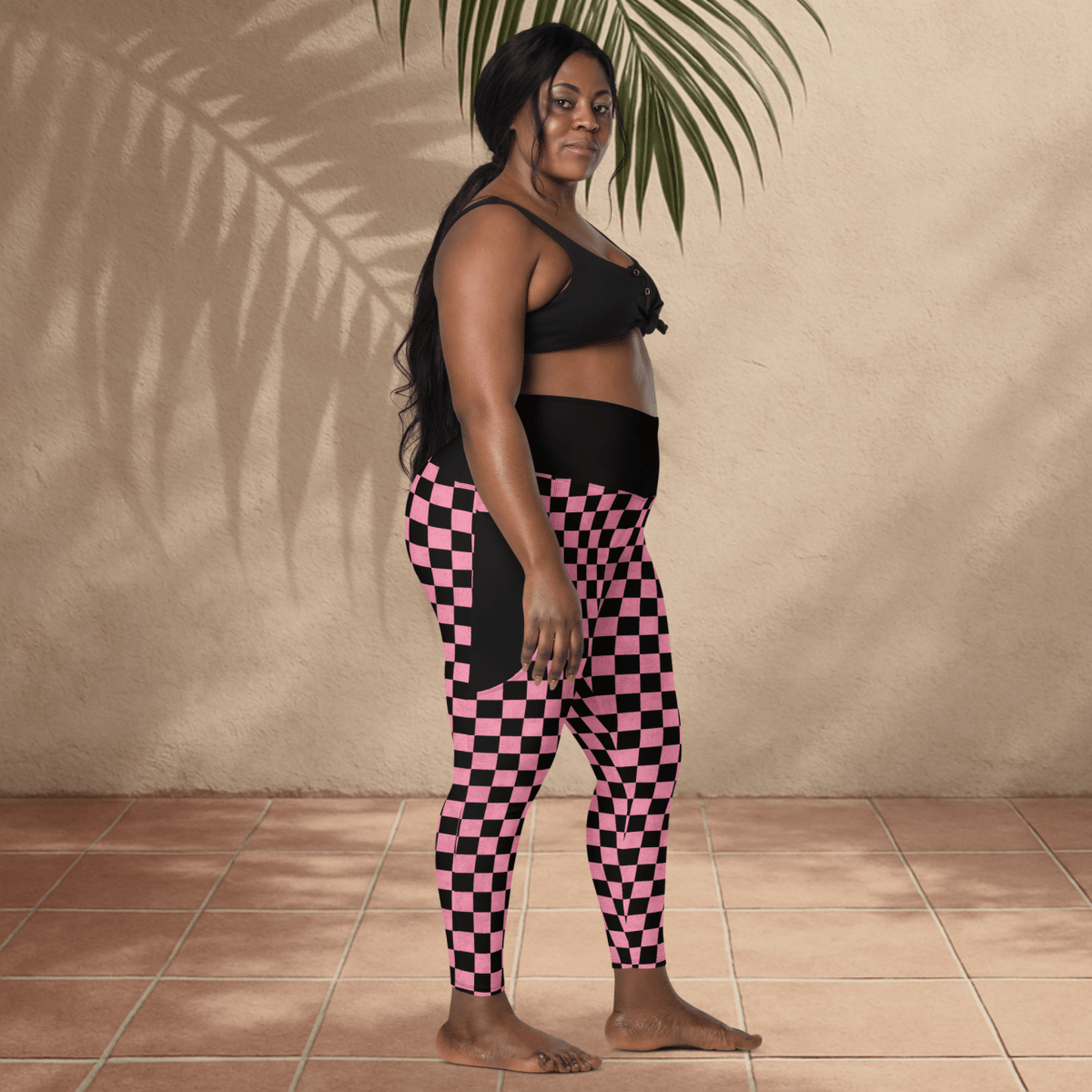Woman wearing black and pink checkered leggings against a beige wall.