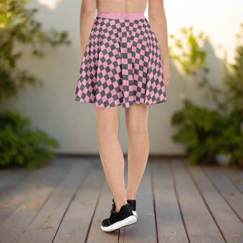 Person wearing a pink and gray checkered skirt standing on a wooden deck with greenery in the background.
