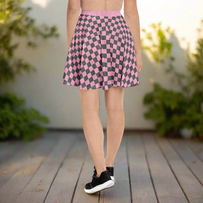 Person wearing a pink and gray checkered skirt standing on a wooden deck with greenery in the background.