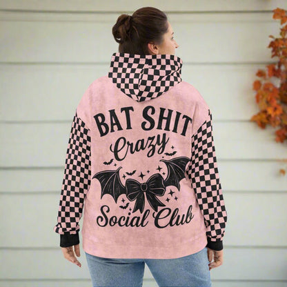 Person wearing a pink hoodie with checkered sleeves and text design on the back.