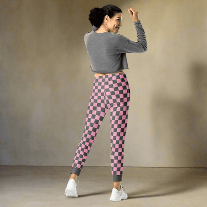 Woman wearing pink and gray checkered leggings with a gray cropped top against a beige wall.