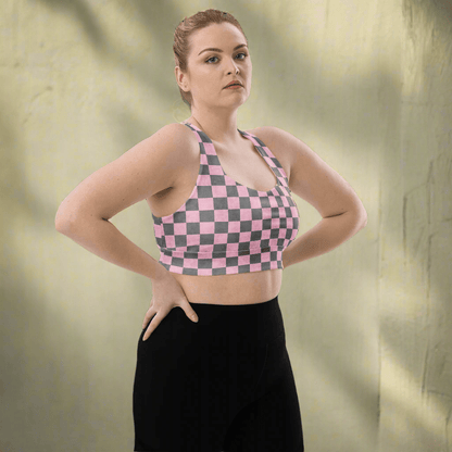 Person wearing a pink and gray checkered sports bra and black leggings on a white background