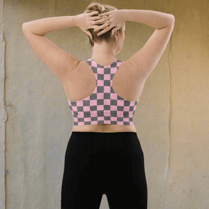 Person wearing a pink and gray checkered sports bra and black leggings on a neutral background