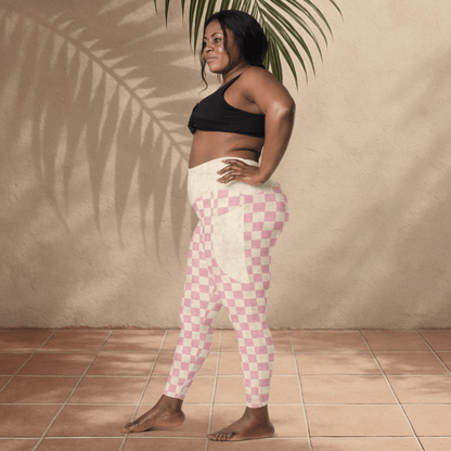 Woman wearing pink checkered leggings and black sports bra against a beige wall.