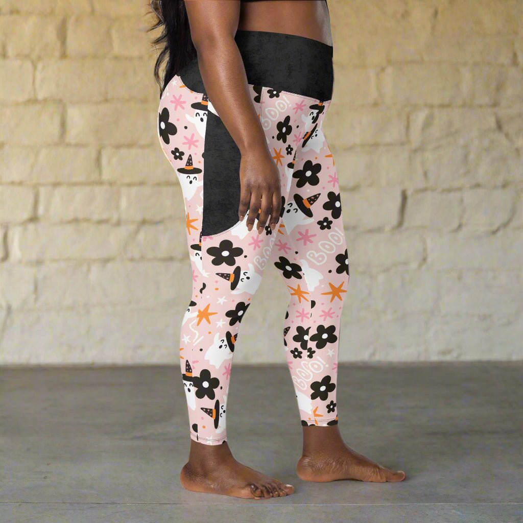 Person wearing pink leggings with halloween pattern against a stone wall.