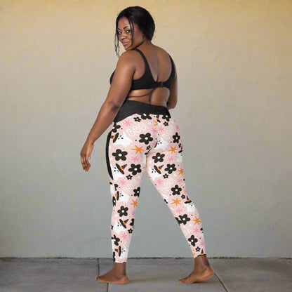 Woman wearing floral halloween leggings and a black sports bra on a white background