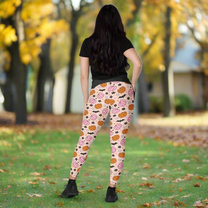 Person wearing pink leggings with Halloween-themed pattern on a neutral background