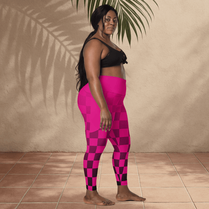 Woman wearing pink checkered leggings and black sports bra standing against a beige wall.
